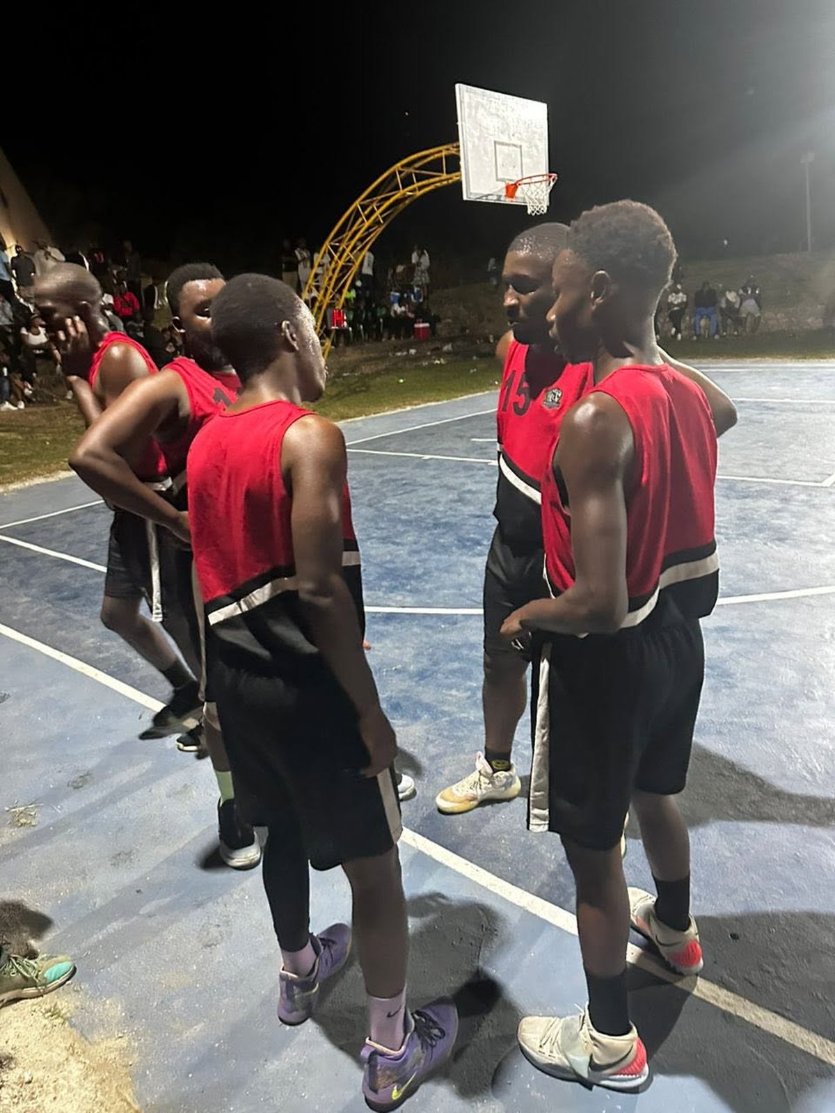 Men's team huddle under floodlights